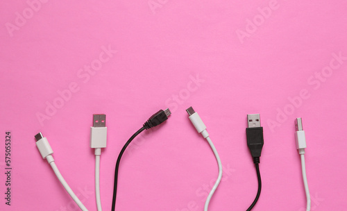 Different usb cables on pink background. Top view
