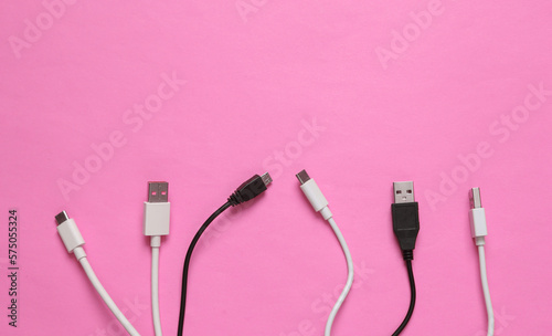 Different usb cables on pink background. Top view photo