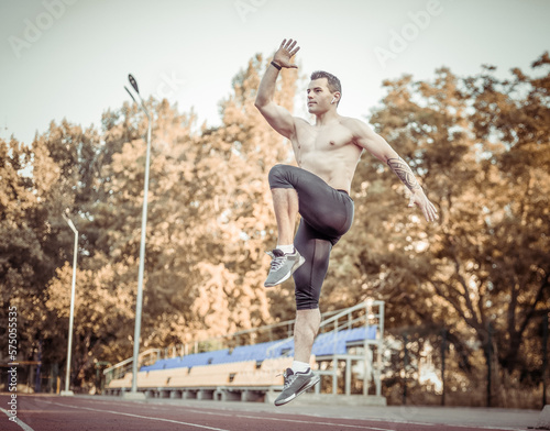 Athletic man with a naked torso practicing jumping up, warming up before running to the stadium. Healthy lifestyle