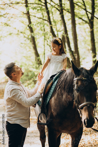Father with his daughter riding horse