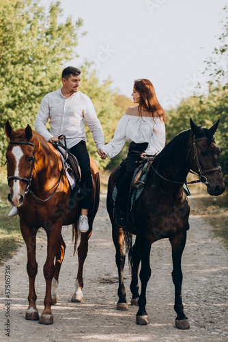 Young couple riding horses together in park