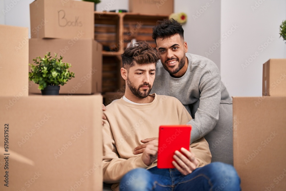 Young couple using touchpad sitting on sofa at new home Young couple using touchpad sitting on sofa at new home