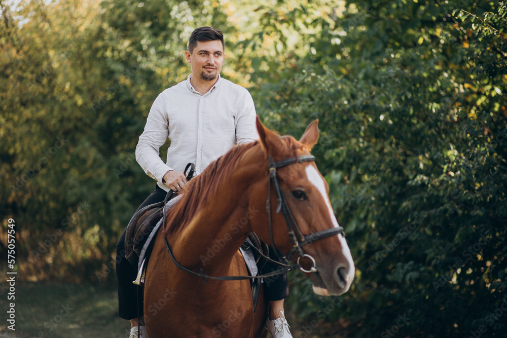 Handsome man riding a horse in forest Handsome man riding a horse in forest