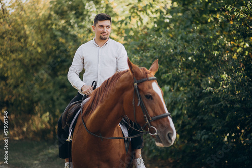 Handsome man riding a horse in forest © Petro