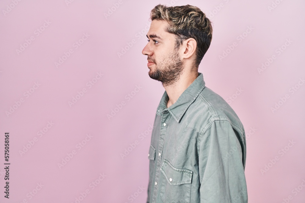 Hispanic man with beard standing over pink background looking to side, relax profile pose with natural face with confident smile. Hispanic man with beard standing over pink background looking to side, relax profile pose with natural face with confident smile.