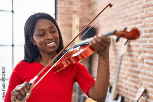 Young african american woman musician playing violin at music studio