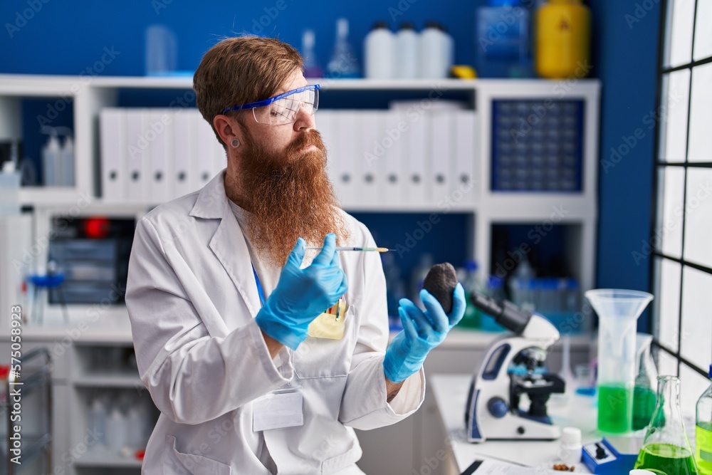 Young redhead man scientist injecting liquid on avocado at laboratory