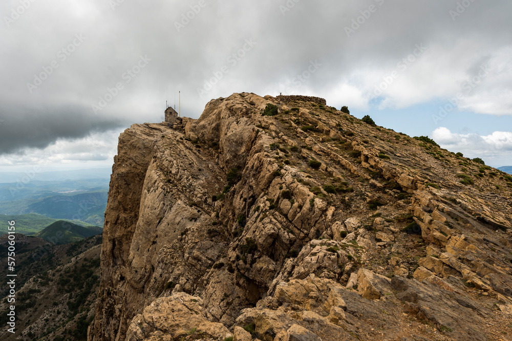 imagen de la cima de una montaña rocosa, con poca vegetación y el cielo nublado imagen de la cima de una montaña rocosa, con poca vegetación y el cielo nublado