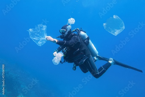 Man scuba diver cleaning plastic in the polluted sea. World ocean contaminated by plastic.