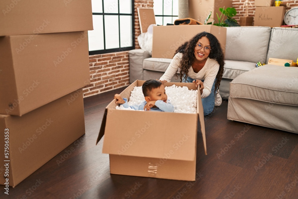 Mother and son playing with cardboard as a car at new home