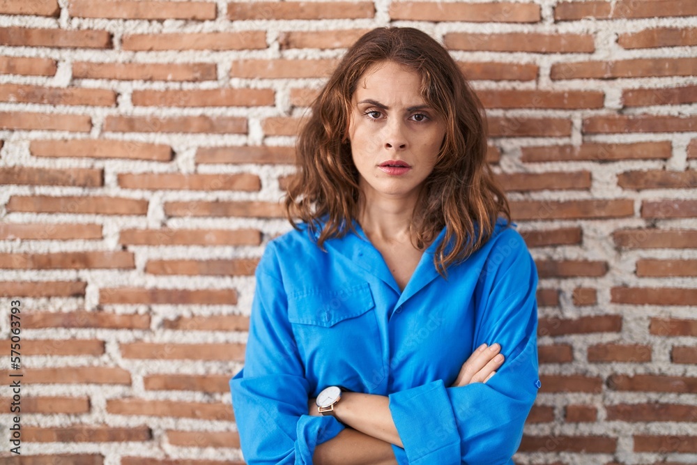 Beautiful brunette woman standing over bricks wall skeptic and nervous, disapproving expression on face with crossed arms. negative person. Beautiful brunette woman standing over bricks wall skeptic and nervous, disapproving expression on face with crossed arms. negative person.