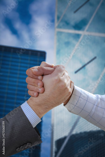 businessmen's  shaking hands after a deal in front of a cityscape building