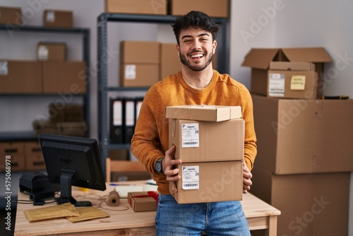 Stampa su tela Hispanic man with beard working at small business ecommerce holding packages celebrating crazy and amazed for success with open eyes screaming excited