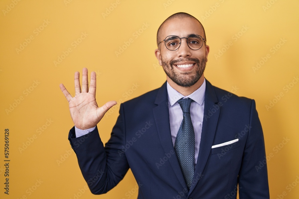 Hispanic man with beard wearing suit and tie showing and pointing up with fingers number five while smiling confident and happy. Hispanic man with beard wearing suit and tie showing and pointing up with fingers number five while smiling confident and happy.