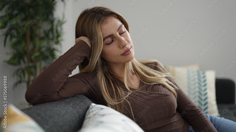 Obraz premium Young blonde woman relaxed with hands on head sleeping on sofa at home