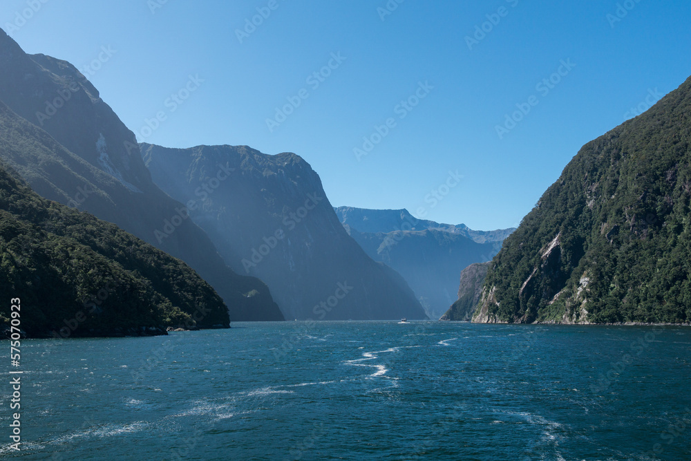 Fjord mit hohen Bergen und blauem Wasser bei blauem Himmel und Sonne. 