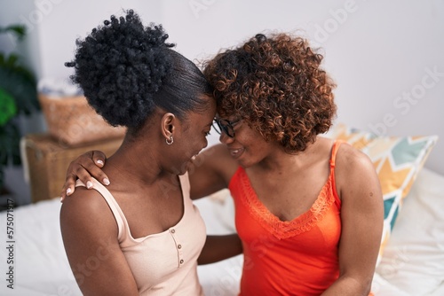 African american women mother and daughter sitting on bed at bedroom