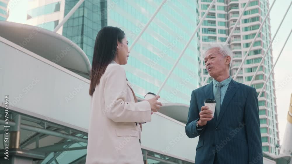 Asian senior mature middle aged businessman and young businesswoman having a discussion and coffee in modern city Asian senior mature middle aged businessman and young businesswoman having a discussion and coffee in modern city