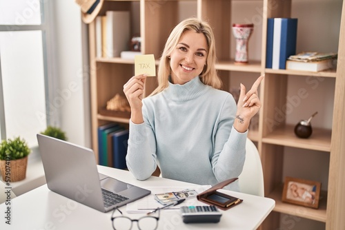 Young caucasian woman calculating money savings smiling happy pointing with hand and finger to the side