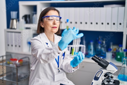 Middle age woman scientist holding test tubes at laboratory