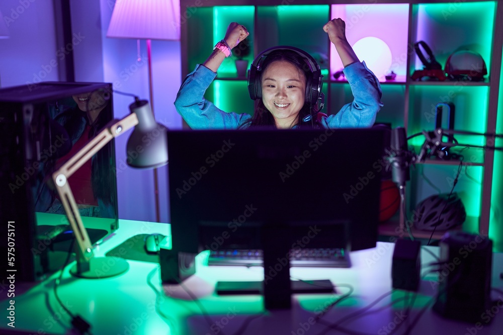 Young chinese woman streamer using computer with winner expression at gaming room Young chinese woman streamer using computer with winner expression at gaming room