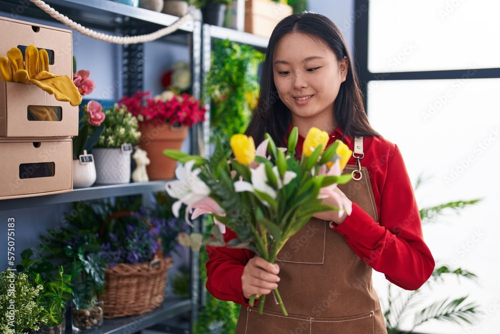 Young chinese woman florist holding bouquet of flowers at flower shop