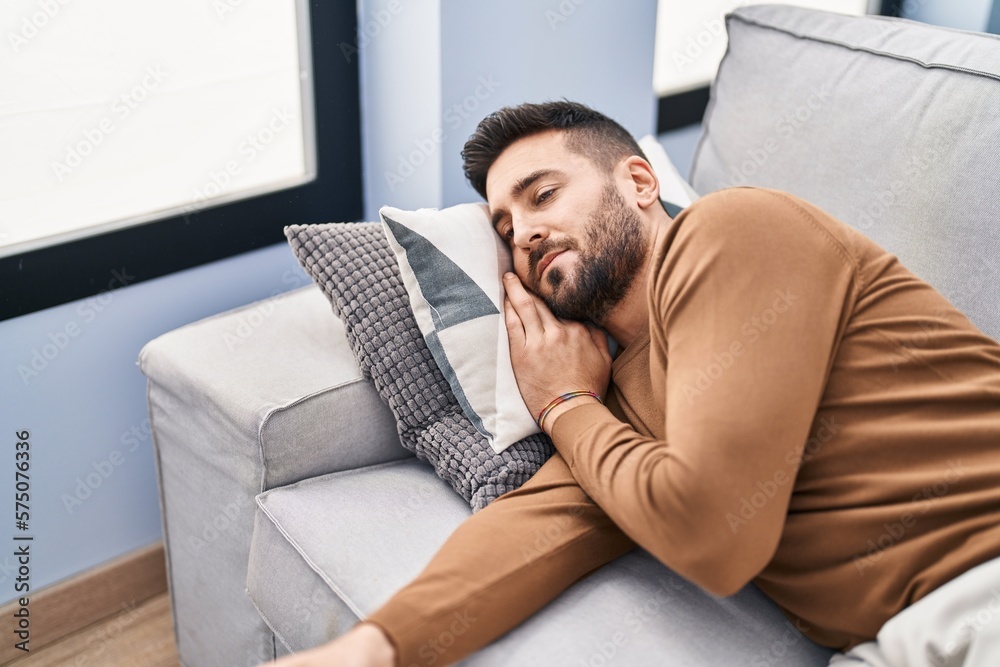 Young hispanic man sleeping on sofa at home