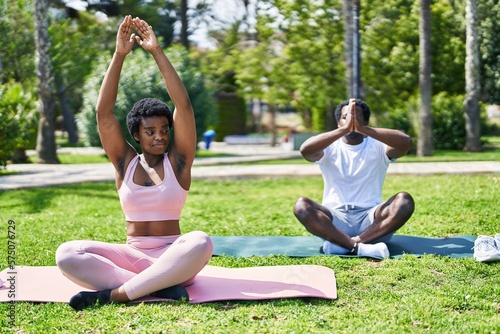 African american man and woman couple smiling confident doing yoga exercise at park
