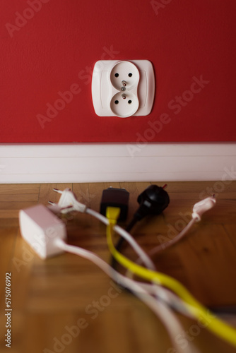 electric socket on the red wall and few different variants of electric plugs 