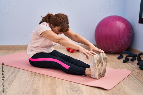 Middle age woman stretching legs at sport center