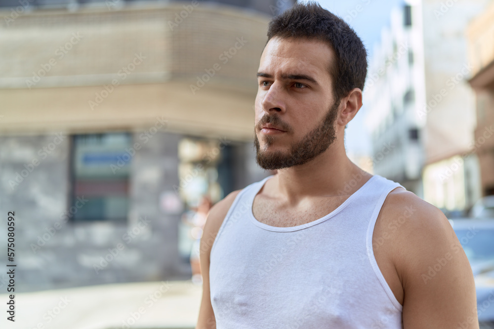 Young hispanic man looking to the side with serious expression at street