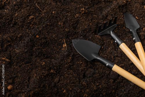 Garden tools on the background of the texture of fertile soil. Gardening concept. Working in the garden. Transplanting indoor plants. Garden shovels and rakes, soil, expanded clay, gardening gloves.