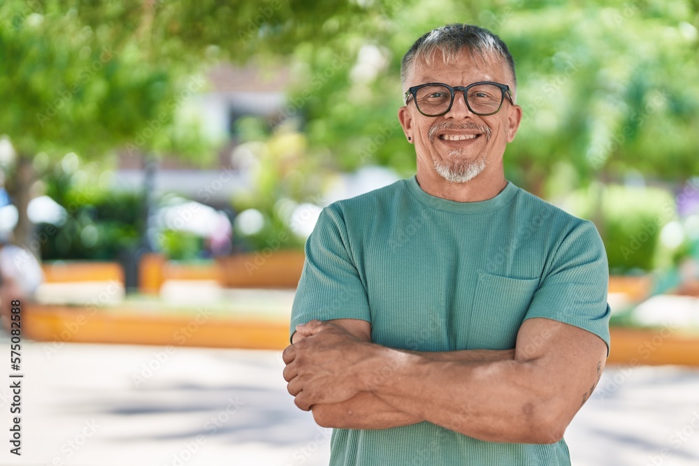 Middle age grey-haired man standing with arms crossed gesture at park Middle age grey-haired man standing with arms crossed gesture at park