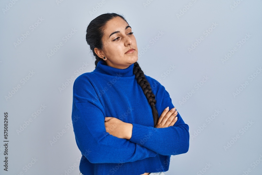 Young hispanic woman standing over isolated background looking to the side with arms crossed convinced and confident Young hispanic woman standing over isolated background looking to the side with arms crossed convinced and confident