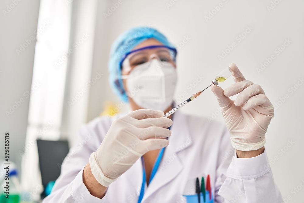 Middle age woman wearing scientist unifor and medical mask holding vaccine at laboratory Middle age woman wearing scientist unifor and medical mask holding vaccine at laboratory