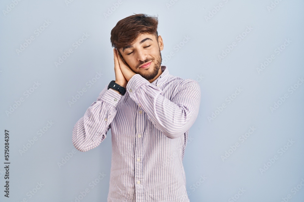 Arab man with beard standing over blue background sleeping tired dreaming and posing with hands together while smiling with closed eyes. Arab man with beard standing over blue background sleeping tired dreaming and posing with hands together while smiling with closed eyes.