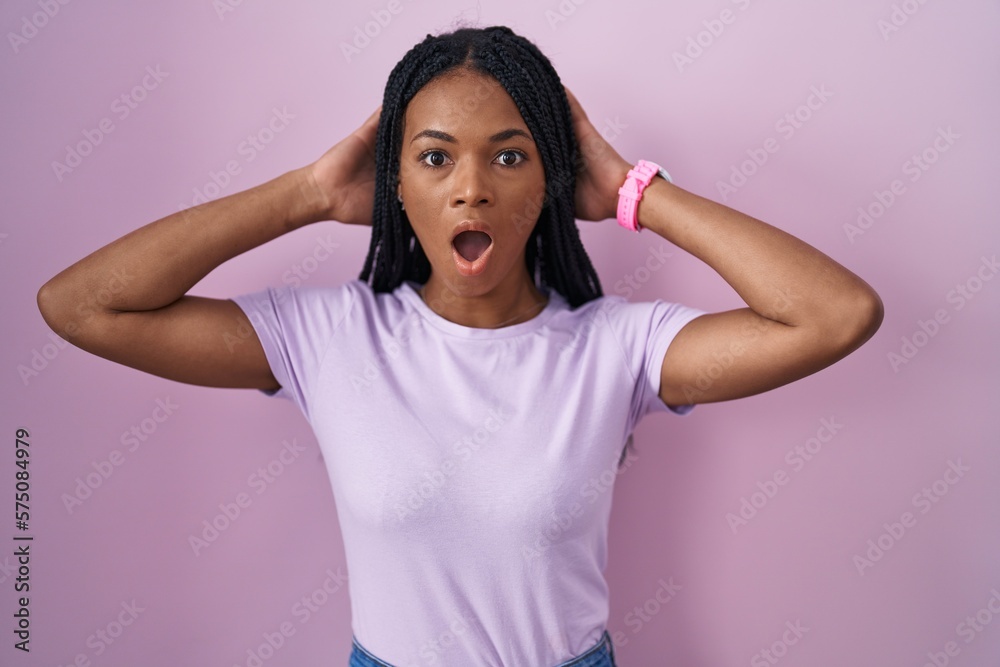African american woman with braids standing over pink background crazy and scared with hands on head, afraid and surprised of shock with open mouth African american woman with braids standing over pink background crazy and scared with hands on head, afraid and surprised of shock with open mouth