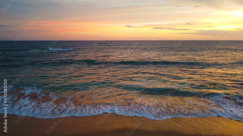Aerial view of the sunset on the beach on the ocean. Beautiful background for tourism and advertising. Tropical coast