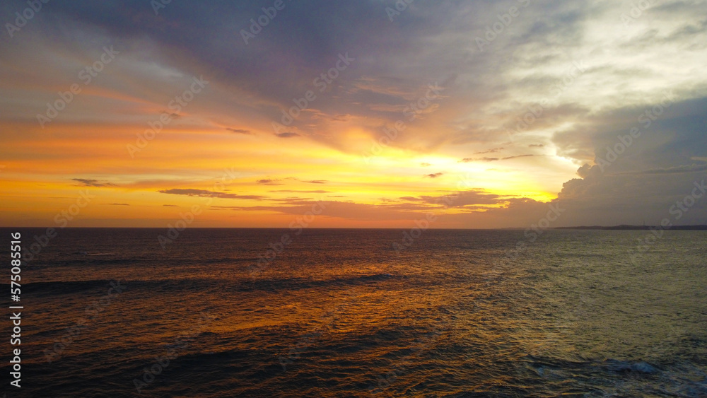 Aerial view of the sunset in an orange sky with clouds. Beautiful background for tourism and advertising. Tropical coast