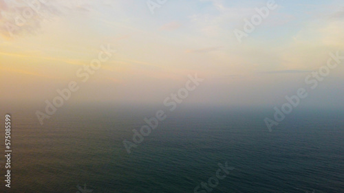Aerial view of the sunset in an orange sky with clouds. Beautiful background for tourism and advertising. Tropical coast © Payllik