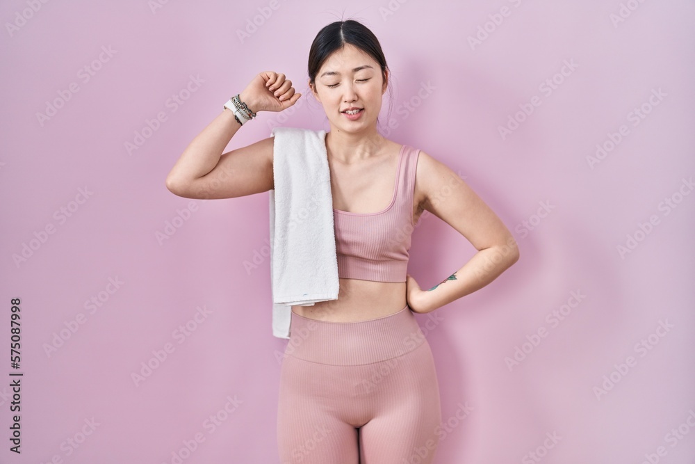 Chinese young woman wearing sportswear and towel stretching back, tired and relaxed, sleepy and yawning for early morning Chinese young woman wearing sportswear and towel stretching back, tired and relaxed, sleepy and yawning for early morning