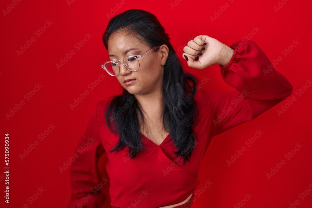 Asian young woman standing over red background stretching back, tired and relaxed, sleepy and yawning for early morning Asian young woman standing over red background stretching back, tired and relaxed, sleepy and yawning for early morning