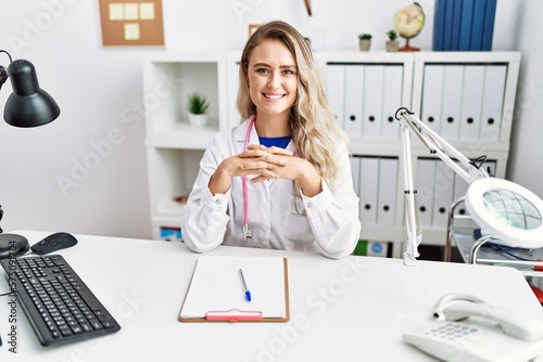Young woman wearing doctor uniform smiling confident at clinic
