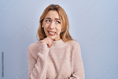 Hispanic woman standing over blue background thinking worried about a question, concerned and nervous with hand on chin © Krakenimages.com