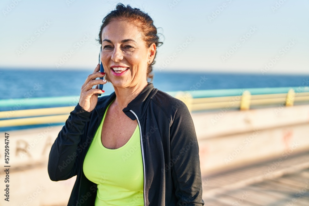 Middle age hispanic woman working out speaking on the phone at promenade Middle age hispanic woman working out speaking on the phone at promenade