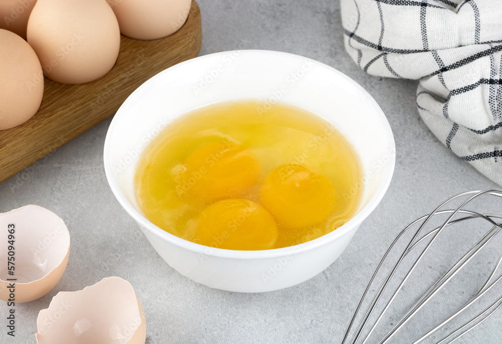 Raw eggs and whisk on a gray background, top view. Pie or cake recipe, breakfast concept, top view. Raw eggs and whisk on a gray background, top view. Pie or cake recipe, breakfast concept, top view.