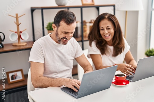 Middle age man and woman couple working sitting on table at home