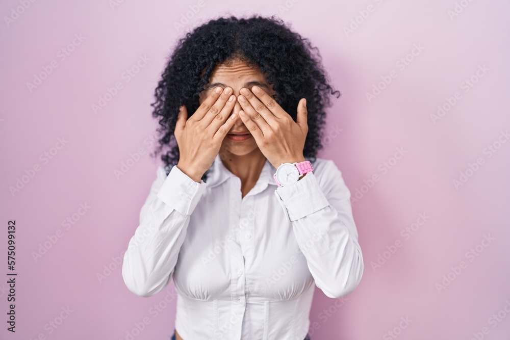 Hispanic woman with curly hair standing over pink background rubbing eyes for fatigue and headache, sleepy and tired expression. vision problem Hispanic woman with curly hair standing over pink background rubbing eyes for fatigue and headache, sleepy and tired expression. vision problem