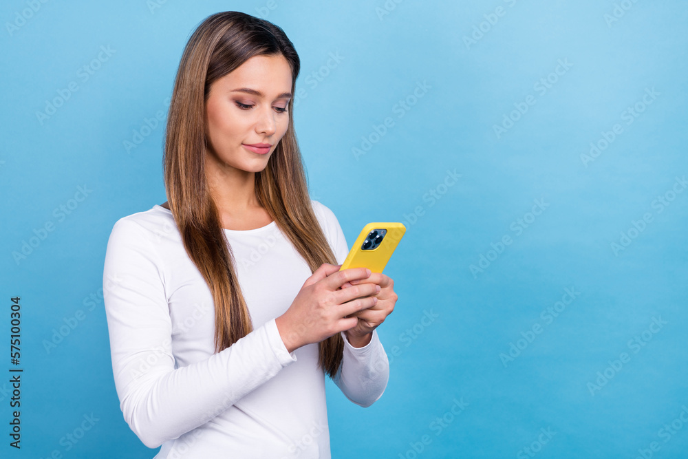 Photo of adorable concentrated focused lady wear stylish clothes use iphone device empty space isolated on blue color background Photo of adorable concentrated focused lady wear stylish clothes use iphone device empty space isolated on blue color background