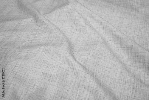 Background with light grey fabric texture with volume pleats. Close-up of a motley woven summer breathable lightweight textile material for trousers, skirts or shirts. Copy space.